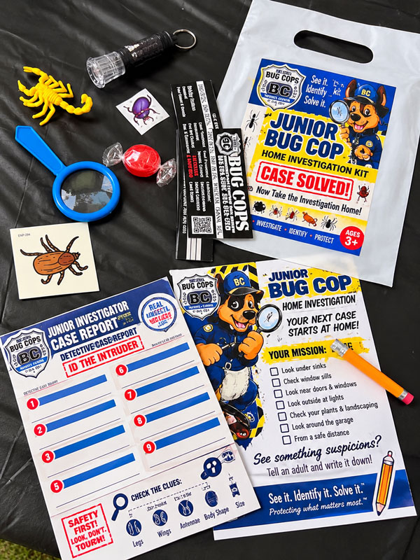 Junior Bug Cop Home Investigation Kit containing a magnifying glass, flashlight, insect toys, educational activity cards, stickers, candy, and investigation materials.